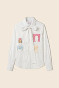 White button down shirt with patchwork featured on the front and a bow tie closer around the neck 